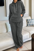 Woman wearing a charcoal grey fuzzy knit lounge set with a drawstring hoodie and straight-leg pants.
