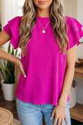 Woman wearing a magenta short sleeve blouse with ruffle trim detail