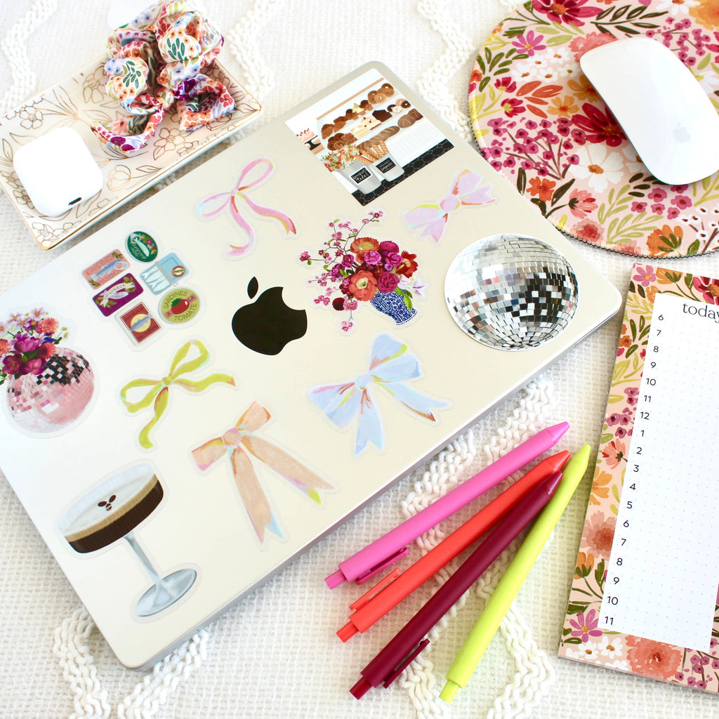 Laptop with decorative stickers on a desk with stationery items