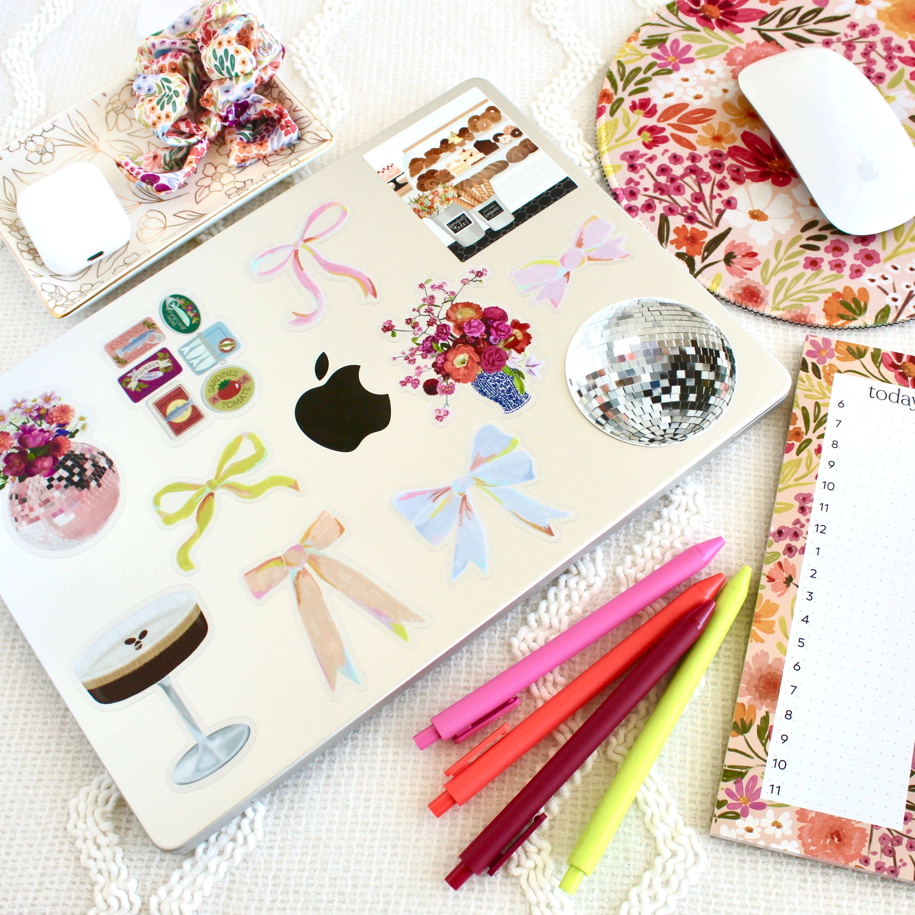 Laptop with decorative stickers on a desk with stationery items