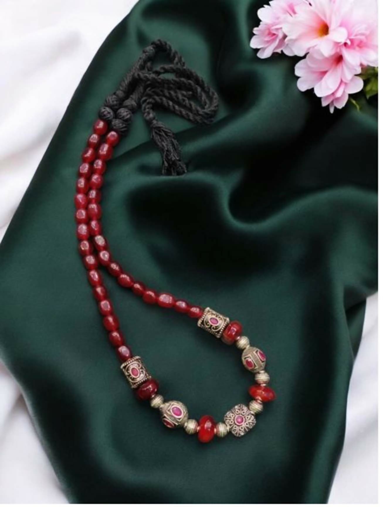 Close up of a red Radha Krishna Tanjore painting pendant on a beaded necklace chain