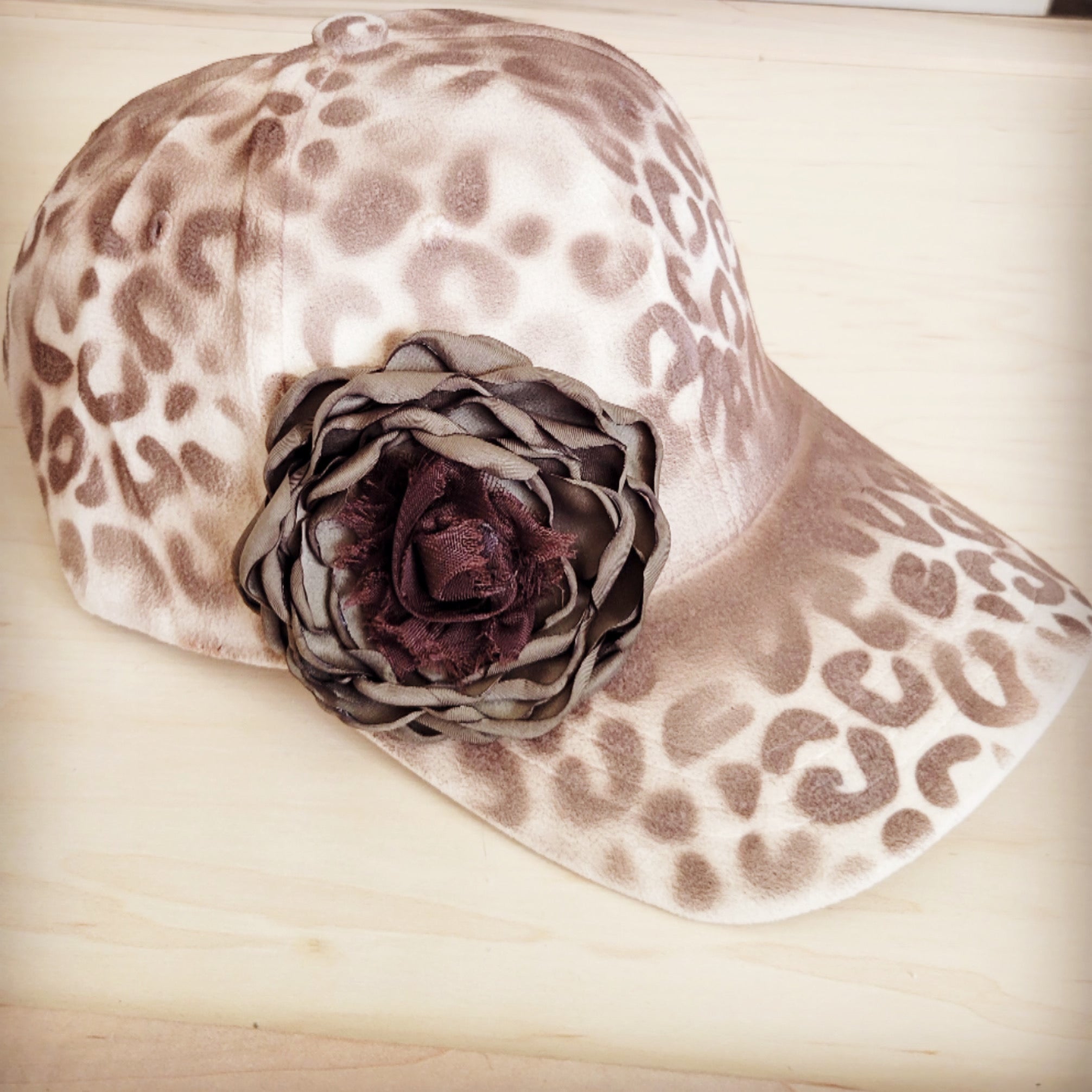 Hand-painted ivory baseball cap with a brown leopard print pattern and a large decorative fabric flower on the side.