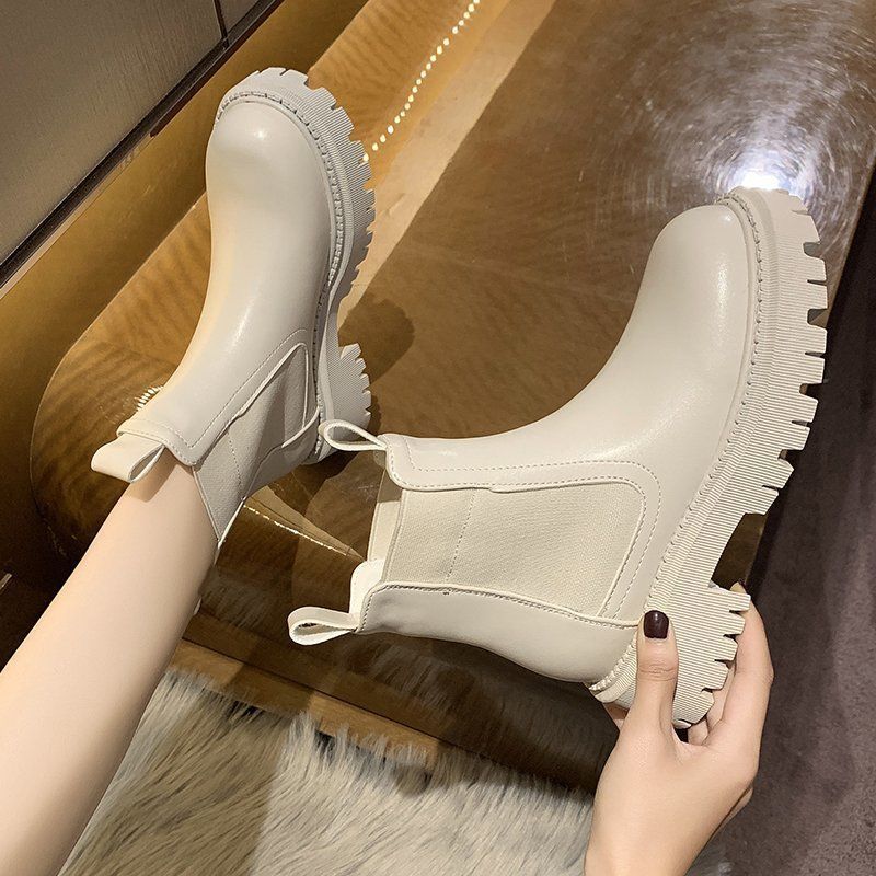 Pair of women's cream waterproof Chelsea boots with thick chunky lug soles, styled on feet.