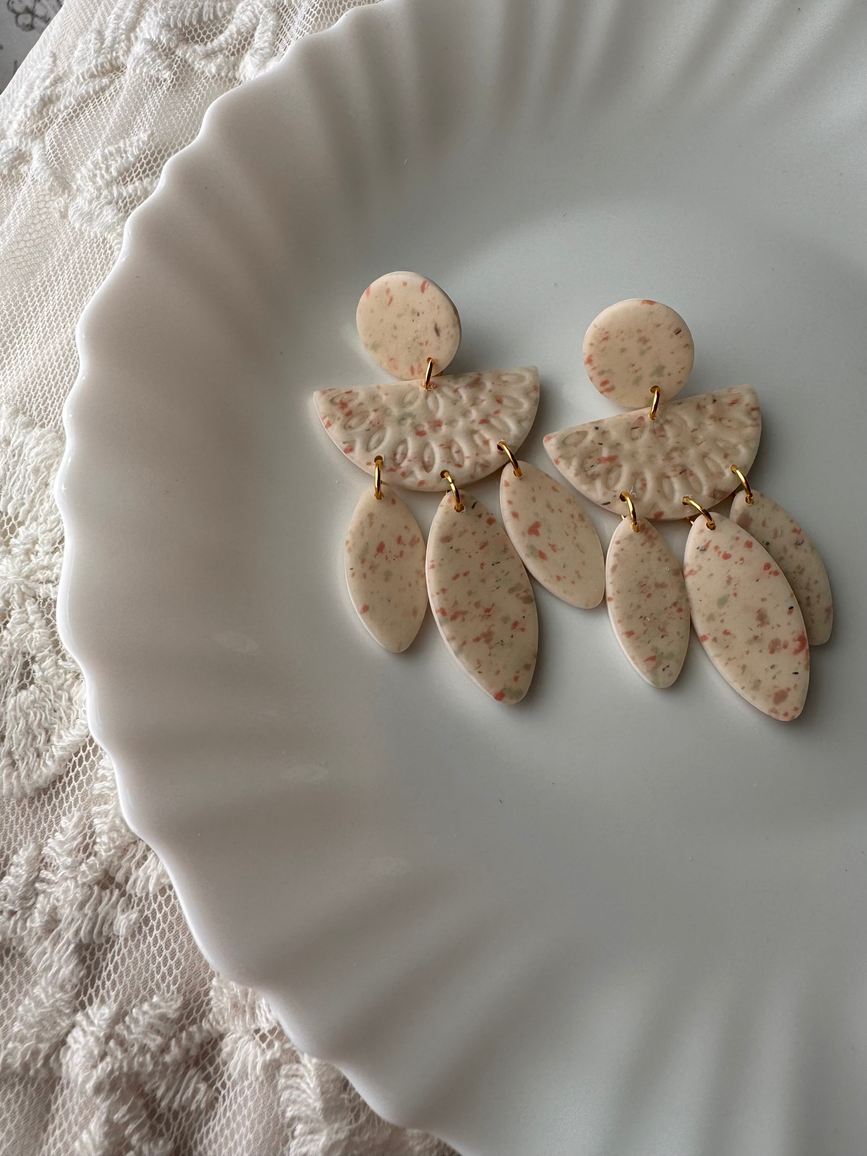Handmade Willow polymer clay earrings featuring a cream terrazzo pattern with leaf-shaped dangles and gold-tone hardware.