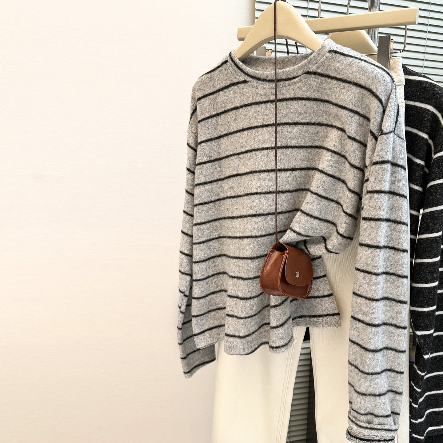 Women's grey and black striped long sleeve fleece-lined sweater on a hanger, showcasing its soft texture and loose fit.