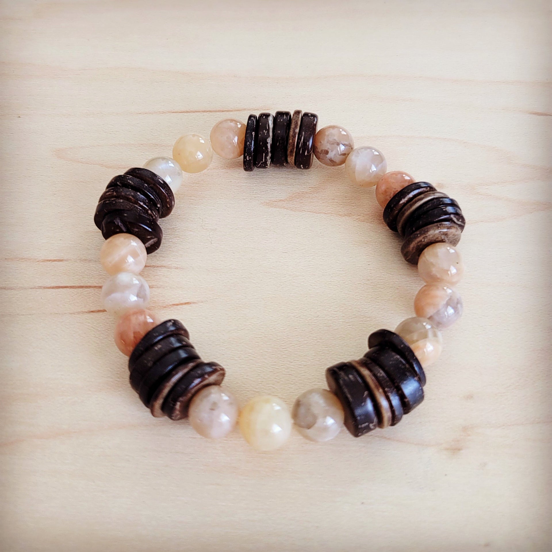Natural agate and dark wood disc beaded stretch bracelet on a light wood surface
