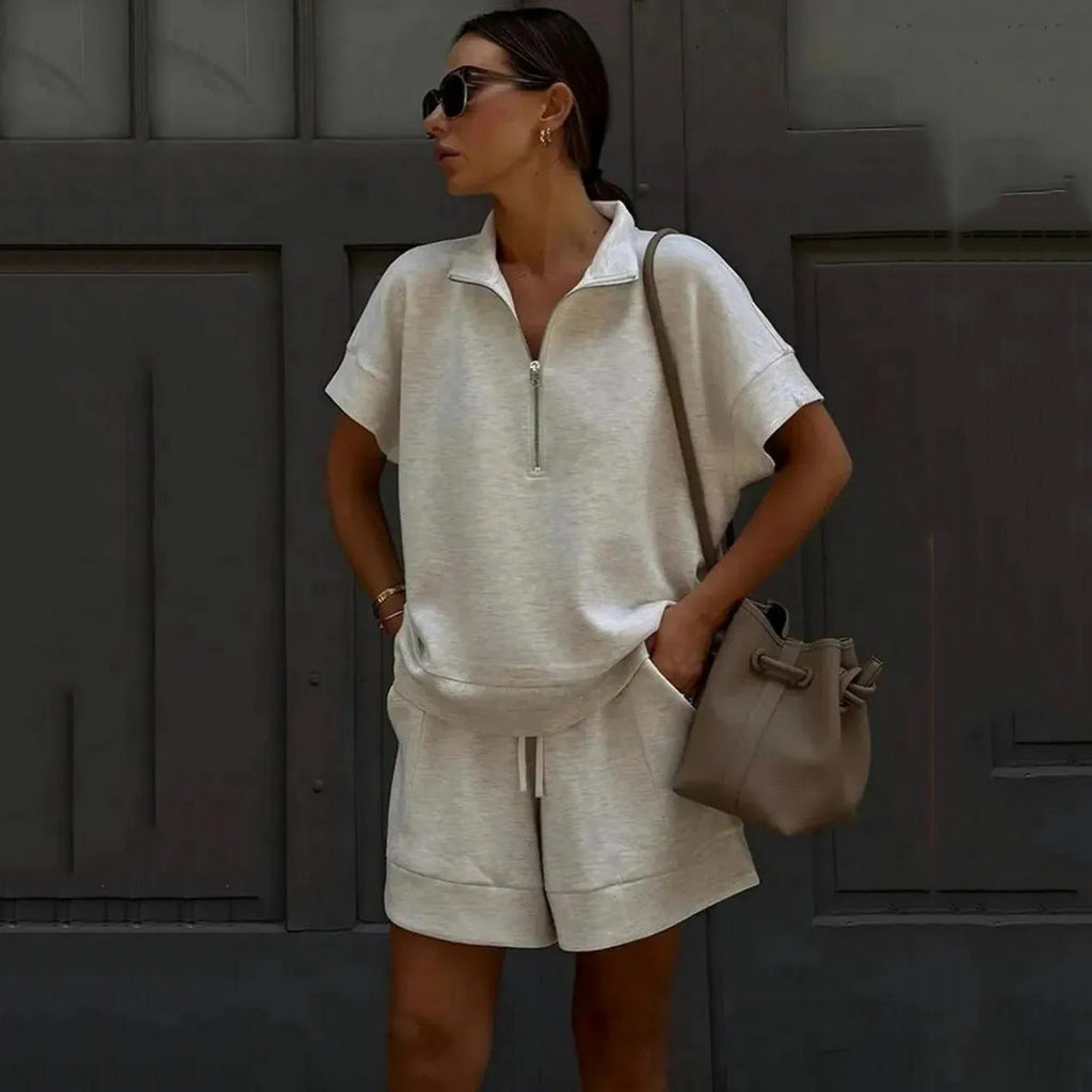 A woman wearing a beige short-sleeve half-zip top and matching shorts set.