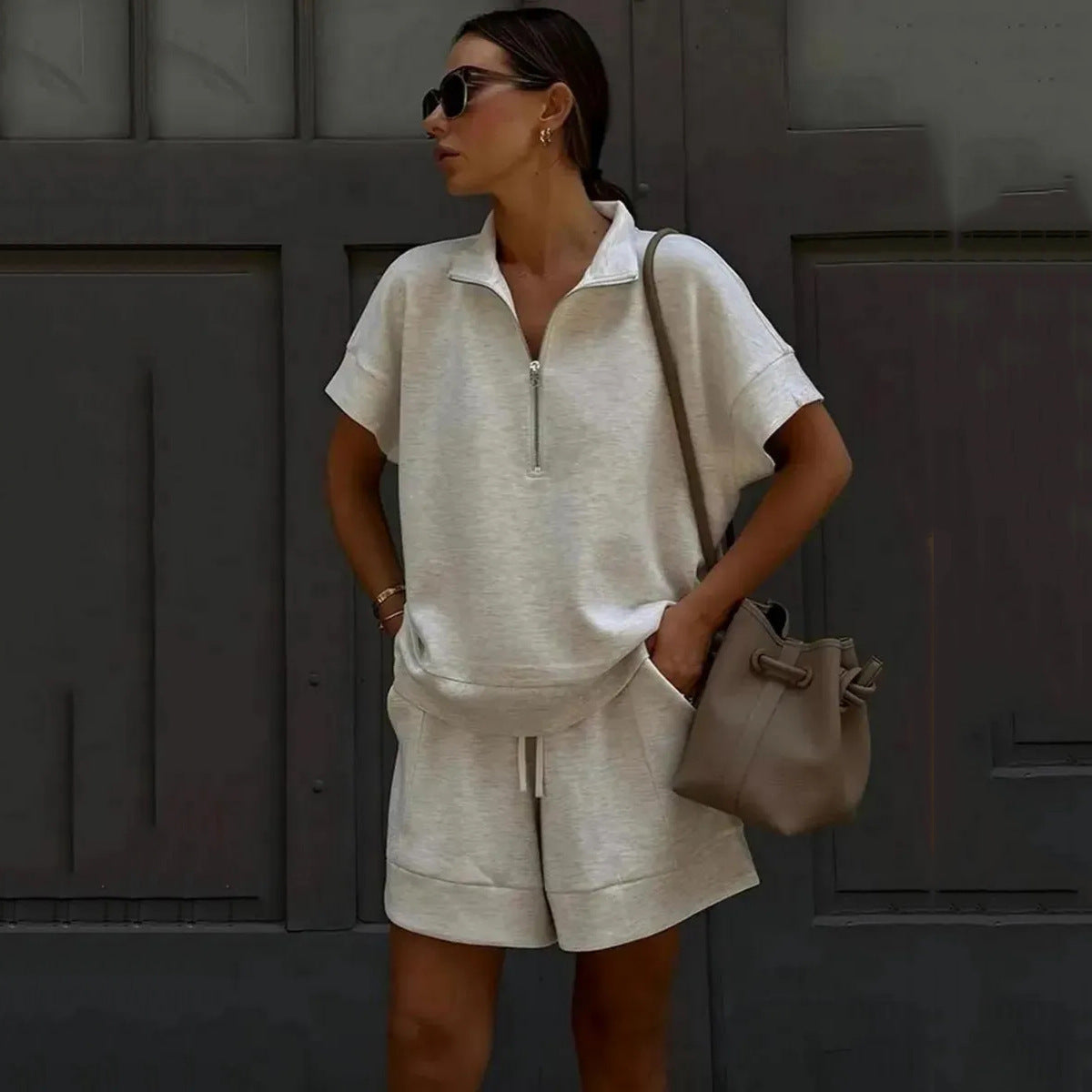 A woman wearing a beige short-sleeve half-zip top and matching shorts set.
