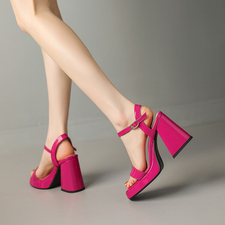 A pair of bright pink patent chunky heel sandals featuring a round toe, platform sole, and thin buckle ankle strap.