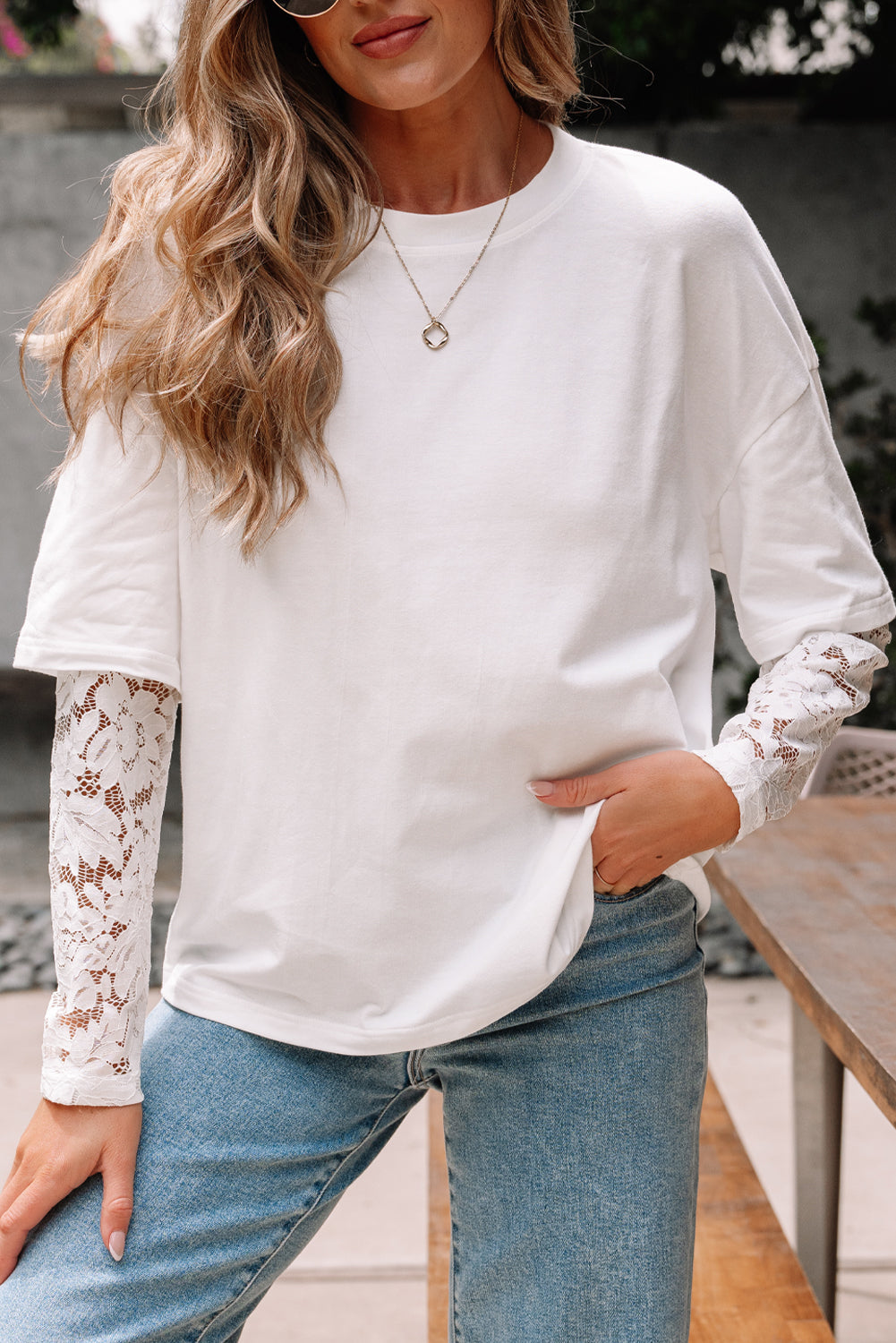 Woman wearing a long sleeve drop shoulder tee with romantic lace insert details in white