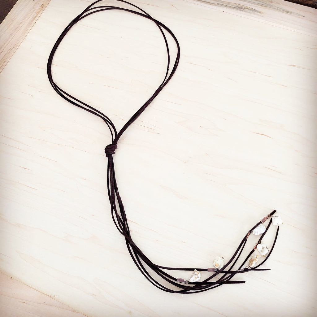 Dark brown leather lasso necklace with raw white turquoise stone accents on a wooden background