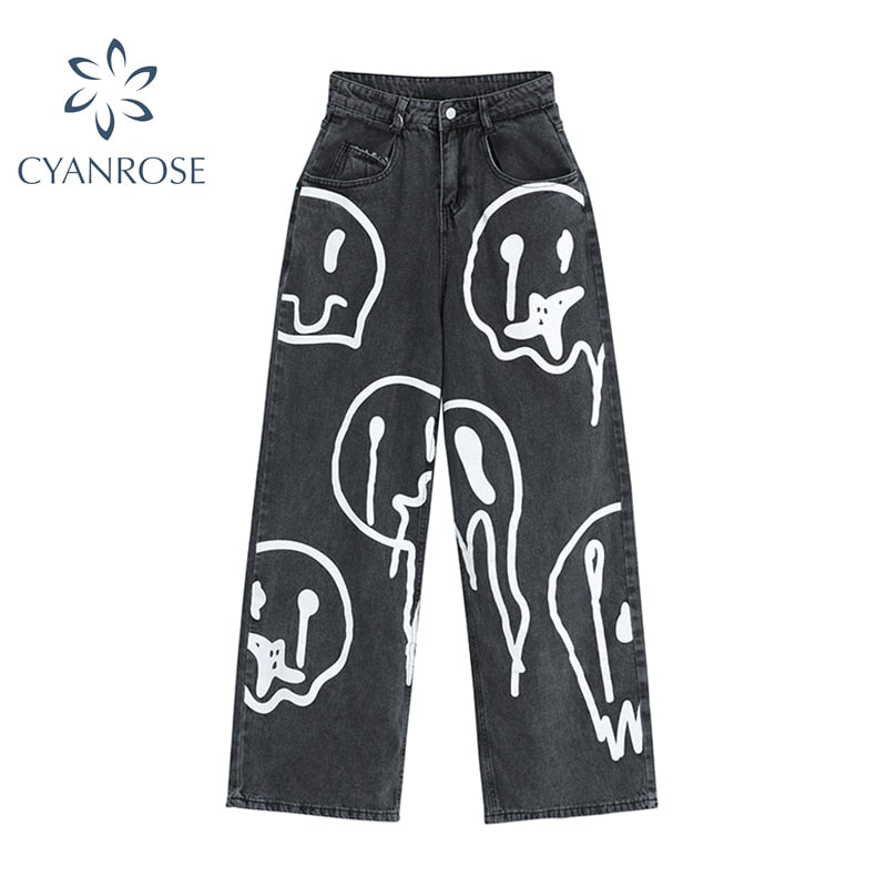 Front view of women's dark wash wide leg denim jeans with white dripping smiley face graphic print, on a white background.