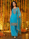 Woman wearing a blue silk embroidered kurti and sharara set with matching dupatta