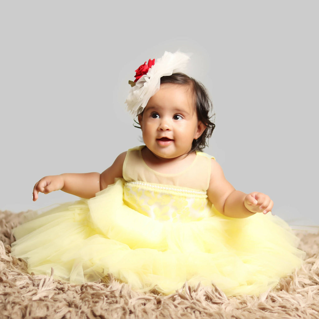 A formal yellow girls gown with an organza bodice and a voluminous layered net skirt.