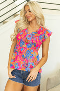 Model wearing a pink floral blouse with smocked bodice and flutter sleeves
