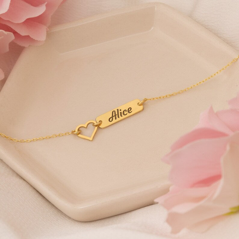 Minimalist Vera Lux gold-tone name bar bracelet featuring a hollow heart accent on a delicate chain