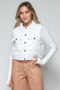 Model wearing a white quilted snap-down cropped vest over a long-sleeved top