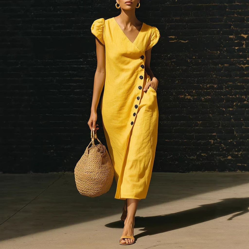 A woman wearing a vibrant yellow midi dress with a V-neckline and side-button details, styled with a straw bag.