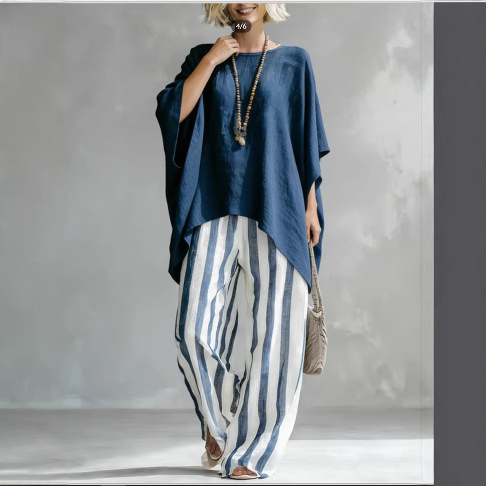 A woman wearing a navy blue batwing top paired with white and navy striped linen wide-leg pants.