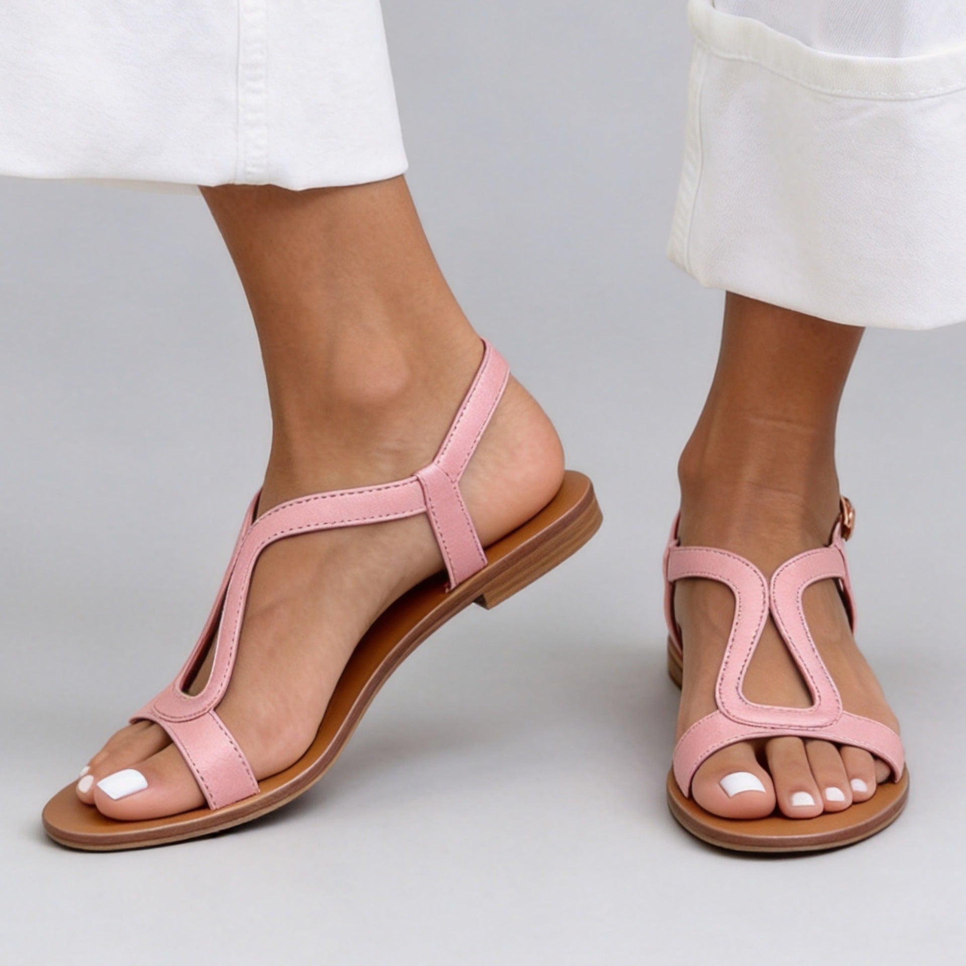 Women's flat open toe T-strap beach sandals featuring a cutout design and buckle closure.