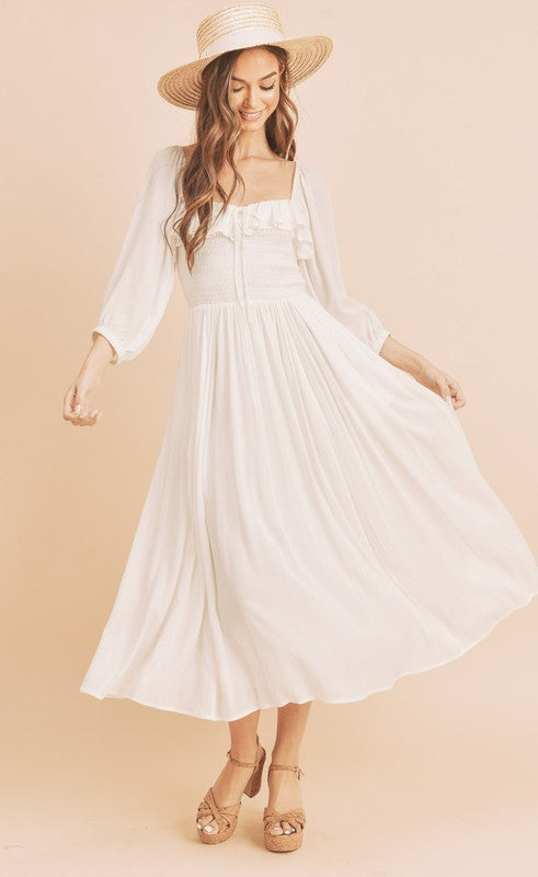 Woman wearing a feminine smocked dress with balloon sleeves and ruffled details