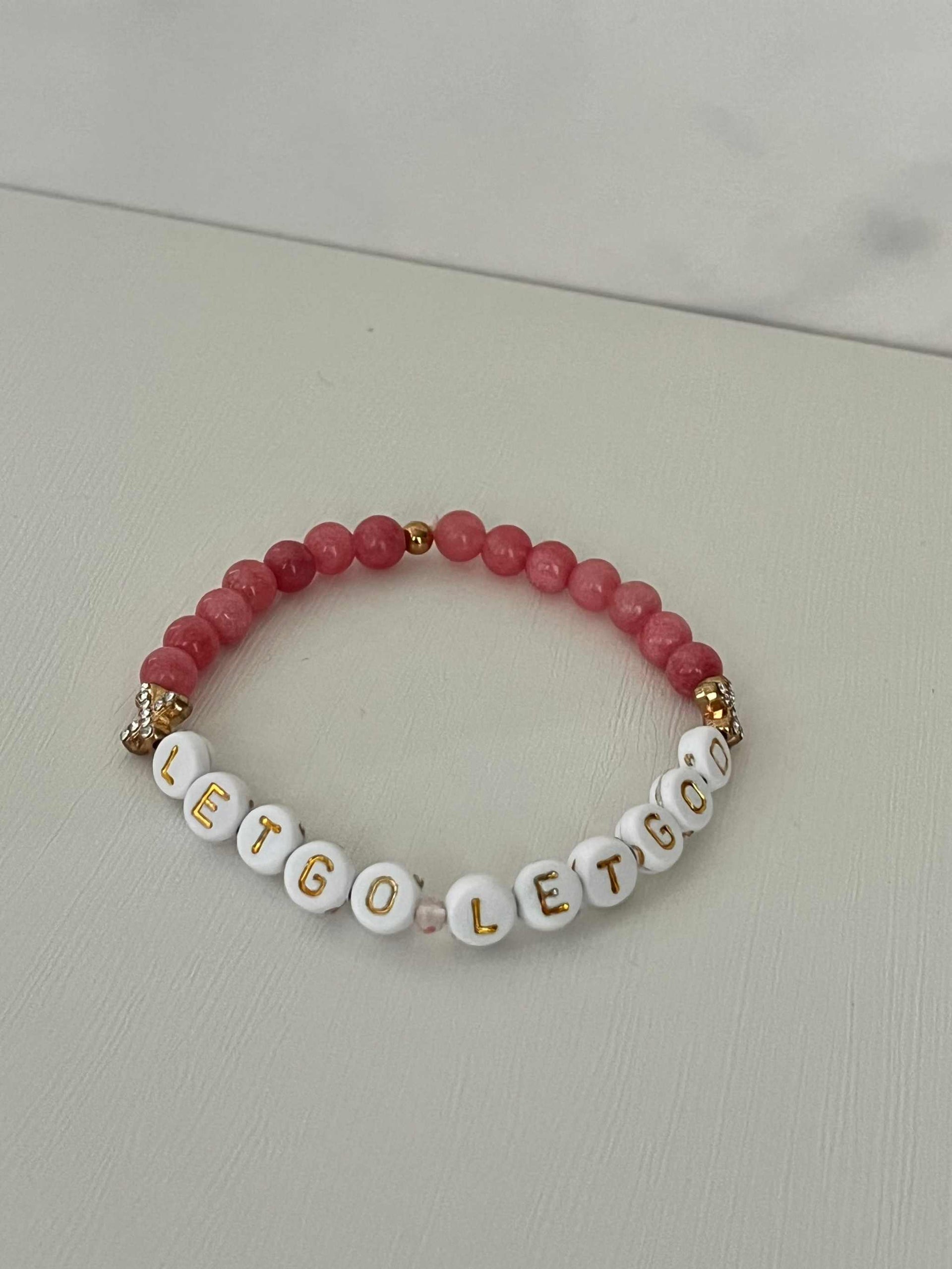 Let Go Let God Bracelet with pink marbled glass beads and gold sequined cross accents.