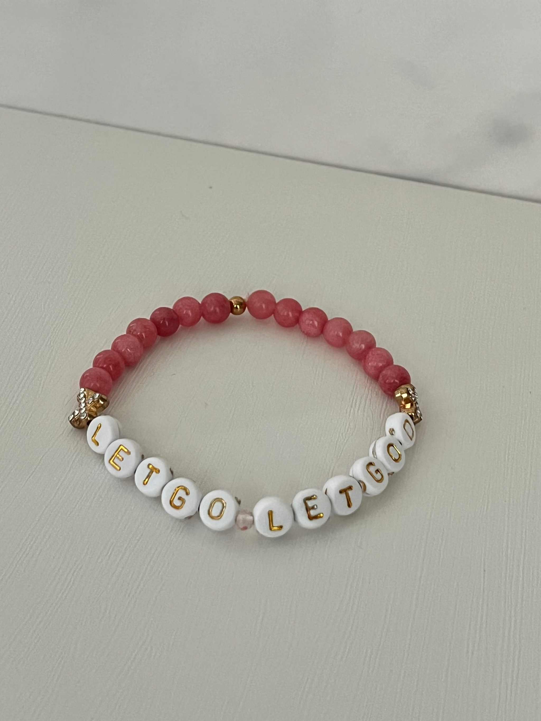 Let Go Let God Bracelet with pink marbled glass beads and gold sequined cross accents.