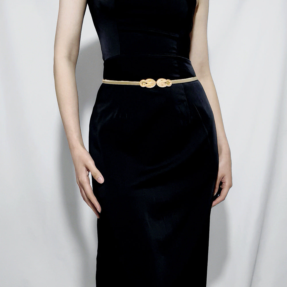 Elegant gold metal waist chain belt worn over a dress to define the waistline
