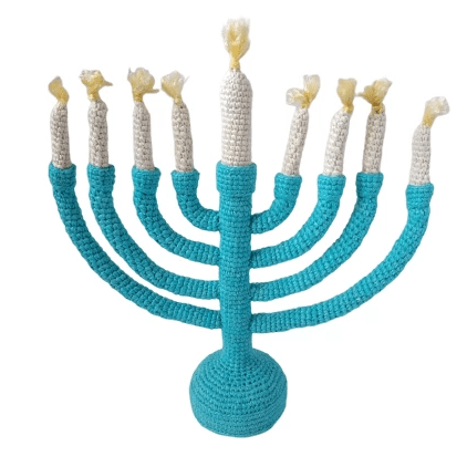 Modern teal and off-white knitted Menorah sculpture standing on a table.