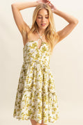 Model wearing a vibrant floral print halter neck mini dress with a tiered skirt and crisscross detailing.