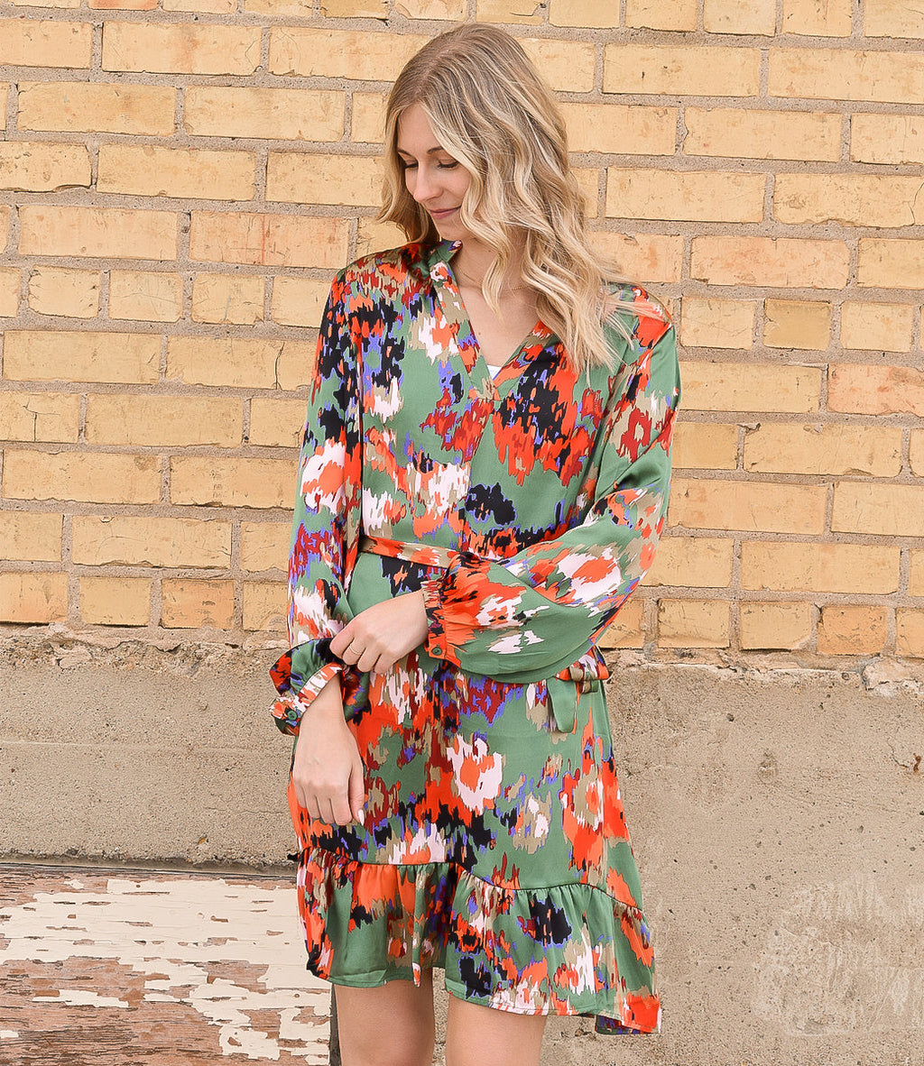 A woman wearing an abstract ruffled drawstring high waist mini dress featuring a playful silhouette.