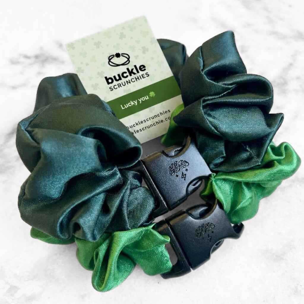 A 2-pack of green hair scrunchies featuring emerald and green apple colors with buckle closures.