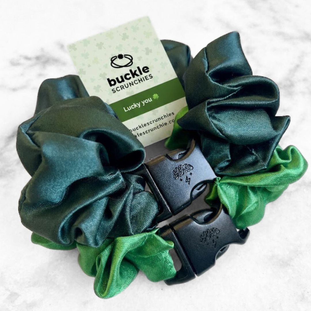 A 2-pack of green hair scrunchies featuring emerald and green apple colors with buckle closures.