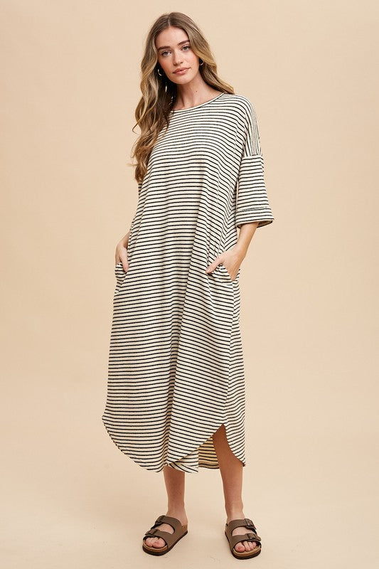 Woman wearing a beige and black striped round neck midi dress in knit fabric