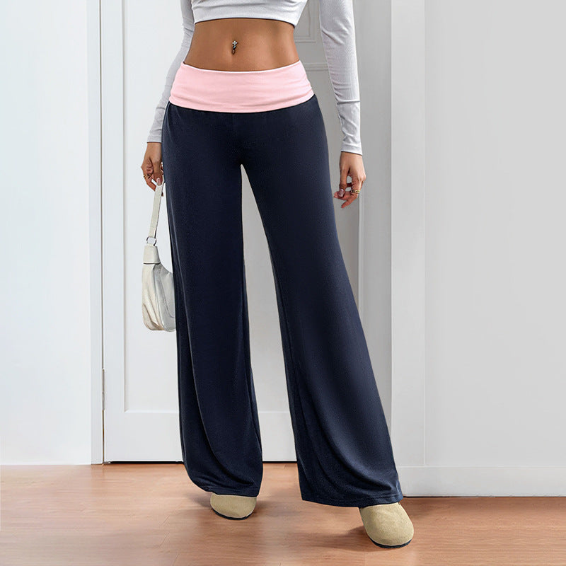 A woman wearing navy wide-leg pants with a contrasting soft pink low-rise waistband