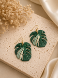 Monstera Yoda handmade polymer clay dangle earrings in green and cream shades on a white background.