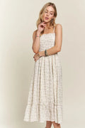 A boho-inspired smocked floral cami dress with a playful ruffled hem in cream and brown.