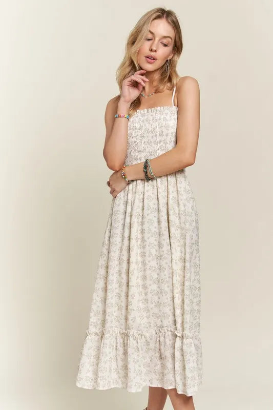 A boho-inspired smocked floral cami dress with a playful ruffled hem in cream and brown.