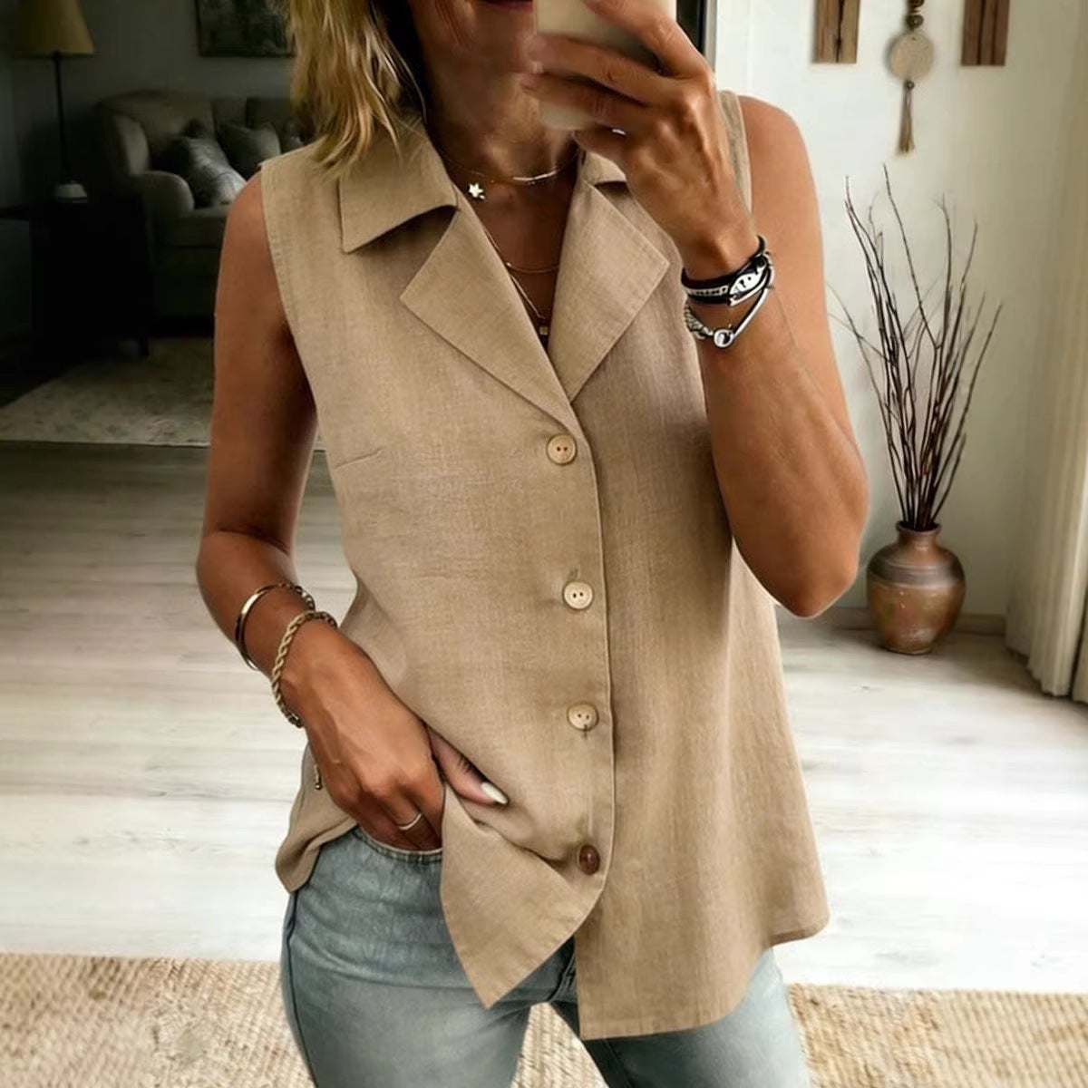 Woman wearing a sleeveless tan button-front vest top paired with light wash jeans