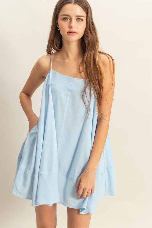 A-line flowy mini cami dress featuring side pockets, styled for a relaxed summer day.