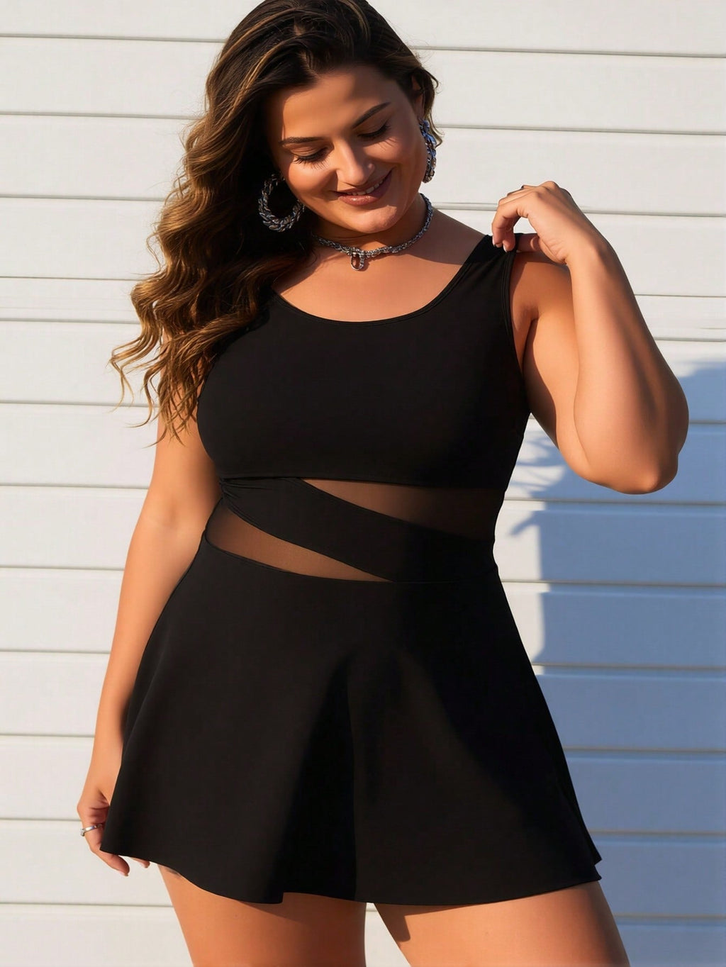 Close-up view of a black swimdress featuring a sheer mesh cutout at the waist and a stylish flared skirt.