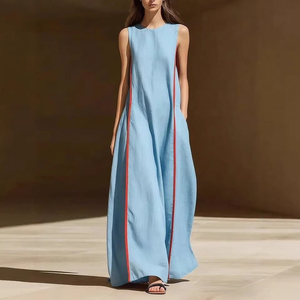 A woman wearing a loose-fitting sleeveless linen maxi dress with a vertical red stripe down the side, available in light blue or navy blue.