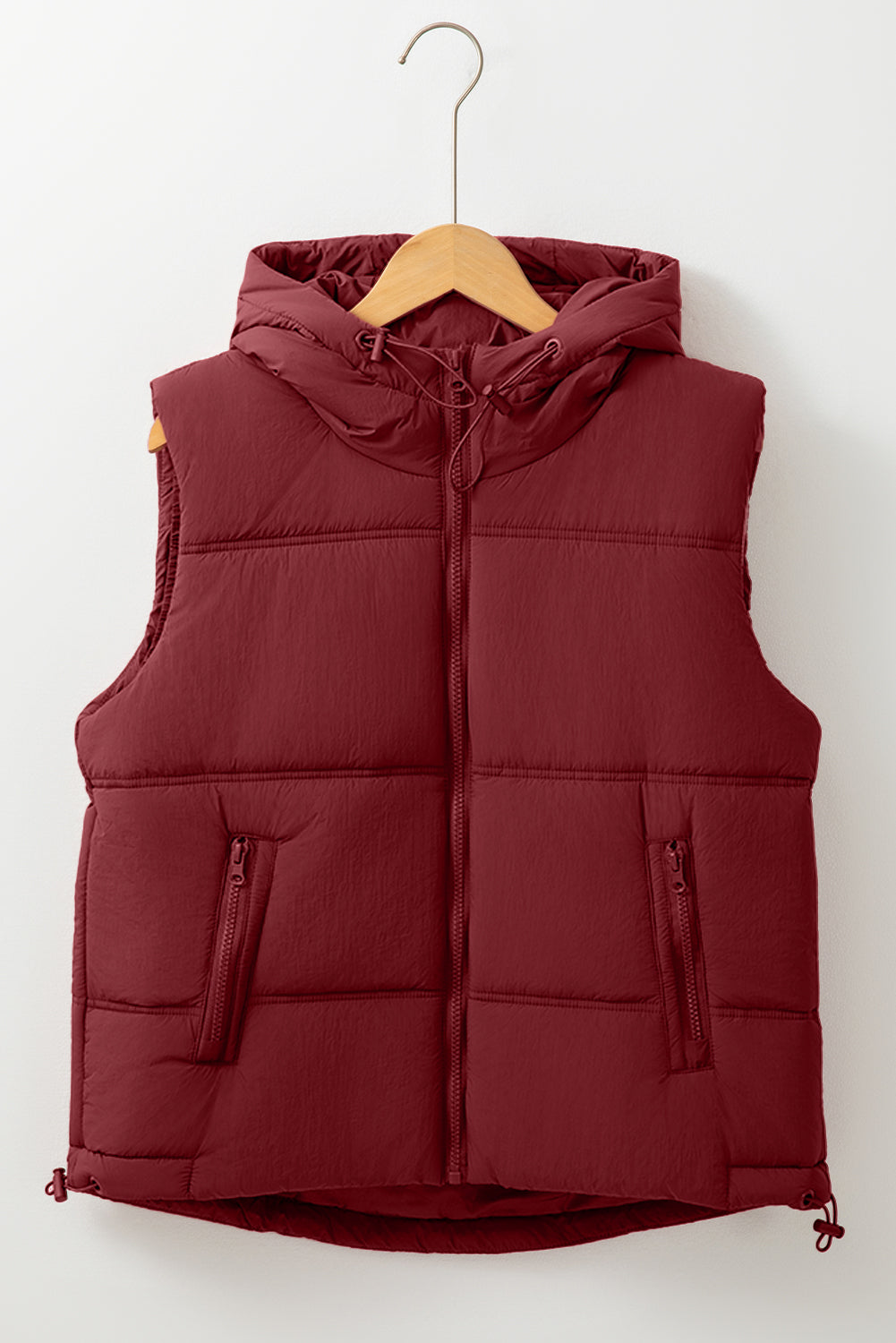 A deep burgundy hooded puffer vest with a front zip closure, two zippered pockets, and a drawstring hem displayed against a white background.