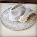 A beige hand-painted western cowgirl hat with a subtle leopard print, featuring a white textured band, a fabric flower, and a white feather.