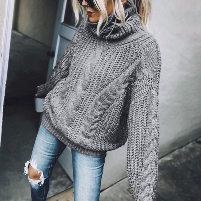 Woman wearing a grey cable knit turtleneck sweater with full-length sleeves and a fold-over collar
