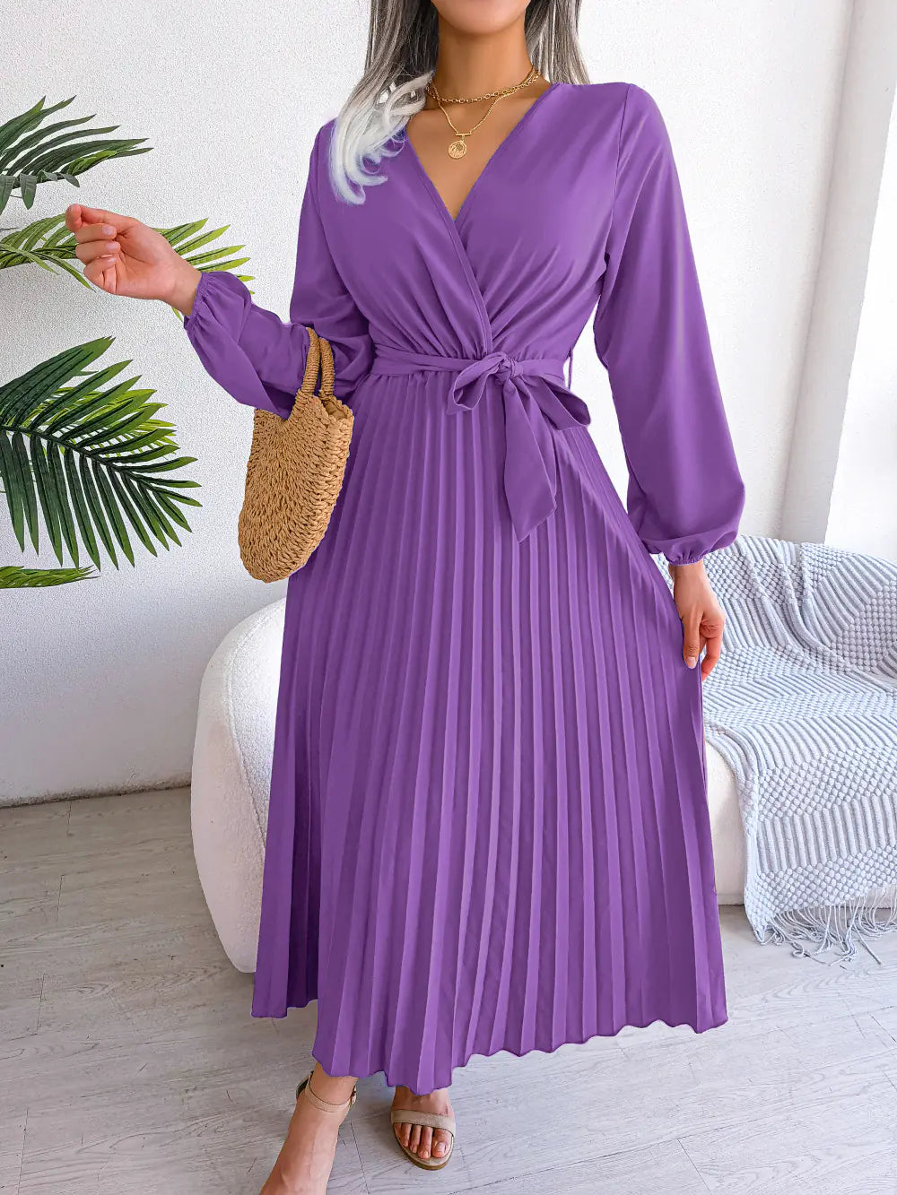Model wearing a pleated long sleeve V-neck maxi dress with a tie waist in purple and burgundy color options.