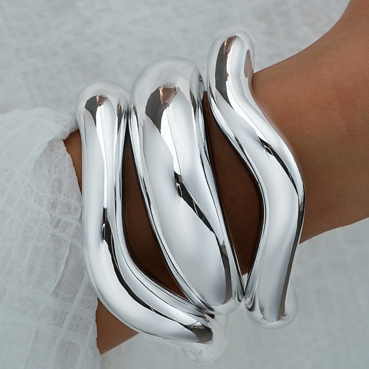 Three wide, high-shine polished silver cuff bracelets for women, modern minimalist style