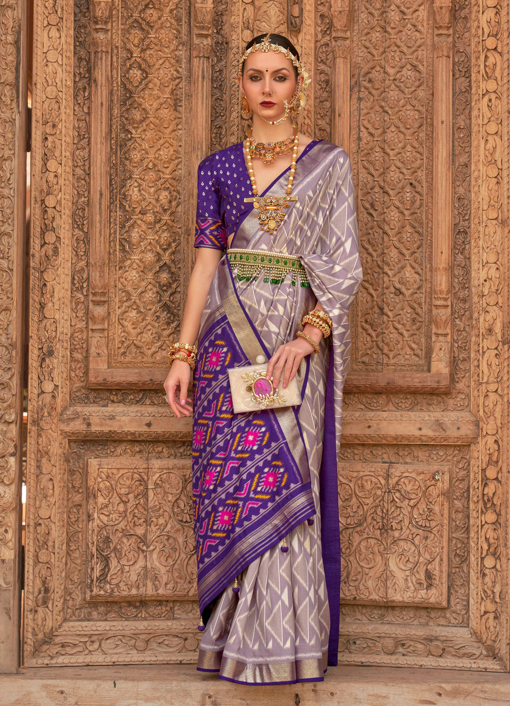 A light grey Patola silk saree with detailed traditional weaving and matching blouse.