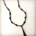 Natural American turquoise beads with dark wood spacers and a leather tassel on a wooden background