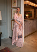 A close-up view of a baby pink traditional silk saree featuring intricate ethnic weaving work and a matching blouse.